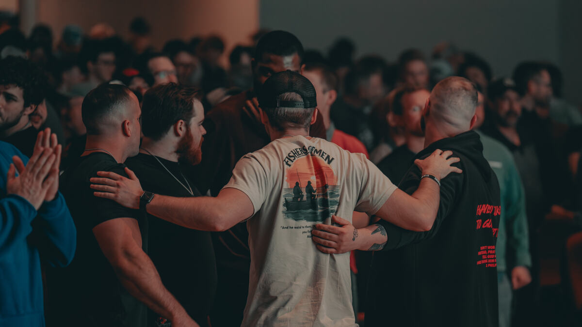 Men standing together with arms around each other